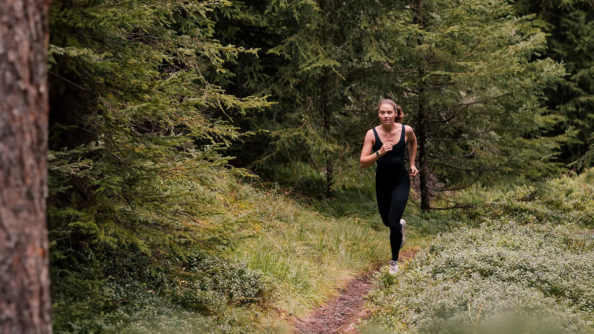 Läuferin auf einem Waldweg in den Alpen